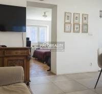 Living room with a television, chairs, and a view of the bedroom in a three-room apartment.