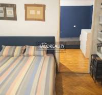 Bedroom in a 3-room apartment with a wooden decor floor and colorful bed linen.