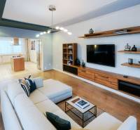 Living room in a 4-room apartment with a wooden decor floor, television, and sofa.