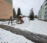 Children are playing in a snowy playground in front of apartment buildings in Považská Bystrica, 4-room apartment.
