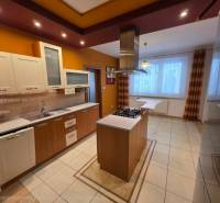 A kitchen in a 4-room apartment with a kitchen island and a wooden decor floor.