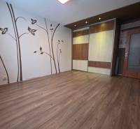A room in a 4-room apartment with a wooden decor floor and decorative wall elements.
