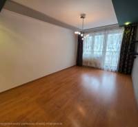 Living room of a 4-room apartment with a wooden decor floor and a large window.