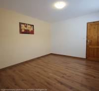 A room with a wooden floor, a painting on the wall, and wooden doors.