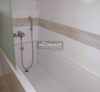 A bathtub in the bathroom of a 2-room apartment with ceramic tiles and a showerhead.