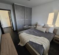 Bedroom in a 2-room apartment with dark flooring, a large wardrobe, and simple furniture.