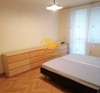 Bedroom in a 3-room apartment with a bed and a dresser on a floor with wood decor.