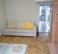 Living room in a three-room apartment with a wooden decor floor and a light sofa.