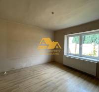 A room with a wooden decor floor and a large window in a family house.