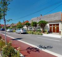A street with family houses in Malacky, cars parked by the road, a cycling path.