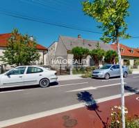 A street in Malacky with family houses, parked cars, and a bicycle lane.