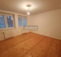 A room in a family house with a wooden decor floor, large windows, and radiators.