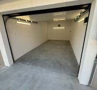 A garage on Slnečná Street in Komárno with a concrete floor and an opening gate.