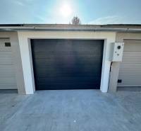 Garages on Slnečná Street in Komárno with dark gates and a concrete surface.
