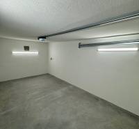 Interior of a garage with a concrete floor and lighting in the garage space.