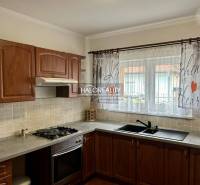 A kitchen in a family house with dark wood decor and colorful curtains.