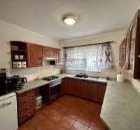 A kitchen in a family house with dark cabinets and appliances, tiled floor.