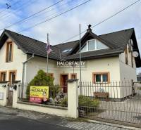A family house in Prievidza, white facade, black roof, front garden, gate with fence.