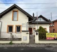 A family house in Prievidza with a white facade, adorned with a garden and a fence.