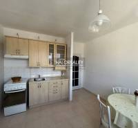 A kitchen in a studio apartment with a kitchenette, dining table, and bright interior.