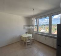 A kitchen in a studio apartment with a view of the city and seating at the table.
