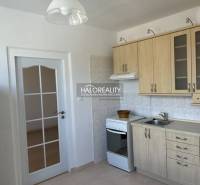 A kitchen with wooden decor, a tiled wall, a white stove, and white doors.