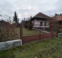 A family house in Dolný Pial surrounded by a garden and a fence, overcast weather.