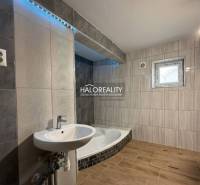 A family house bathroom with a bathtub, a sink, and a wooden decor floor.