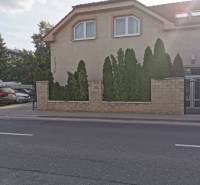 Office building on Šamorínska Street in Senec, with parking and coniferous trees.