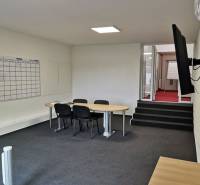 Offices with a conference table, chairs, a board, and a TV on the wall.