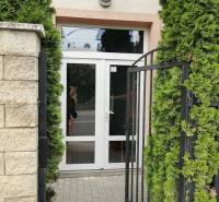 The entrance door on Šamorínska Street in Senec surrounded by greenery and a fence.