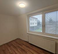 A room in a 3-room apartment with a wooden decor floor and a large window with a view.