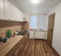 Kitchen in a 3-room apartment, floor with wood decor, white kitchen unit.