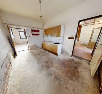 The interior of a family house with a simple kitchen unit and a worn-out floor.