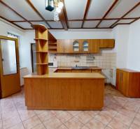 A kitchen in a family house with ceramic tiles and a wooden decor kitchen unit.