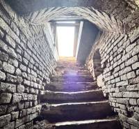 Stone stairs in the basement of a family house with a vaulted ceiling and a light opening.
