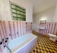 A bathroom in a family house with a bathtub, a sink, and checkered tile flooring.