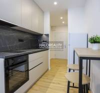 A kitchen unit with a marble design and a floor with a wood design in a studio apartment.