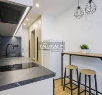 A kitchen corner with a black countertop and a bar counter in a studio apartment.
