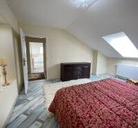 Attic bedroom with a bed, wooden decor flooring, and a skylight in a family house.