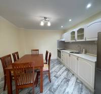 A kitchen in a family house with a wood-patterned floor and a dining table.