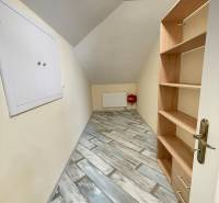 A narrow hallway with a shelving unit and a wooden decor floor in a family house.