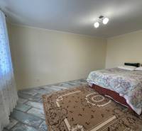 A bright bedroom in a family house with a bed and a patterned carpet.