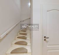 A staircase with carpet mats in a family house with white walls and doors.
