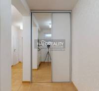 A hallway in a family house with tiles, a mirrored wardrobe, and white walls.