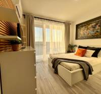Bright bedroom with a bed and decorative pillows, wooden decor flooring, studio apartment.