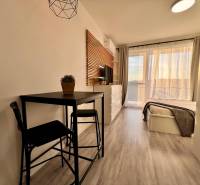 Interior of a 1-room apartment with a wooden decor floor, table, and bed.