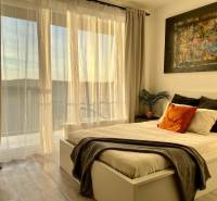 Bedroom with a bed, painting, and curtains in a studio apartment with wood-patterned flooring.