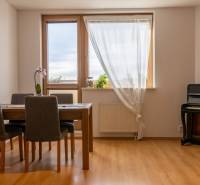 Dining area in a 3-room apartment with a piano and a wooden decor floor.