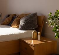 Bright bedroom in a 3-room apartment with a wooden bed, nightstand, and a plant.